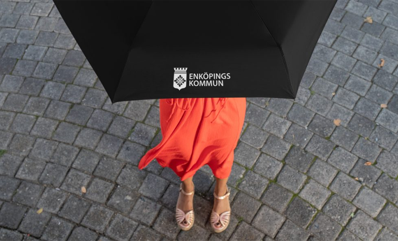 Ett svart uppfällt paraply med trycket "Enköpings Kommun".