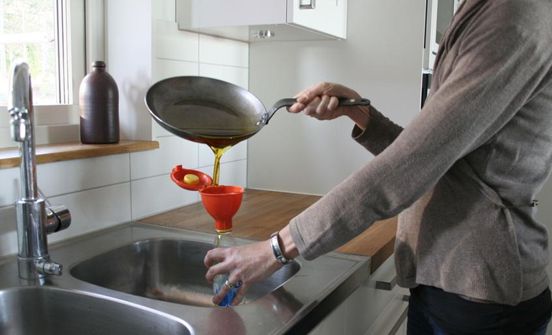 En person häller ut matfett i miljötratten för att inte skapa stopp i vasken