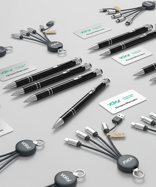 En översikt av Voky-märkta profilprodukter som inkluderar flera svarta pennor, vita namnskyltar och cirkulära multiladdningskablar.