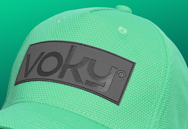 Voky-logotypen stämplad på en svart läderlapp som fästs på framsidan av en grön keps