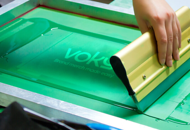 Voky-logotypen genomgår screentryck på en textil yta